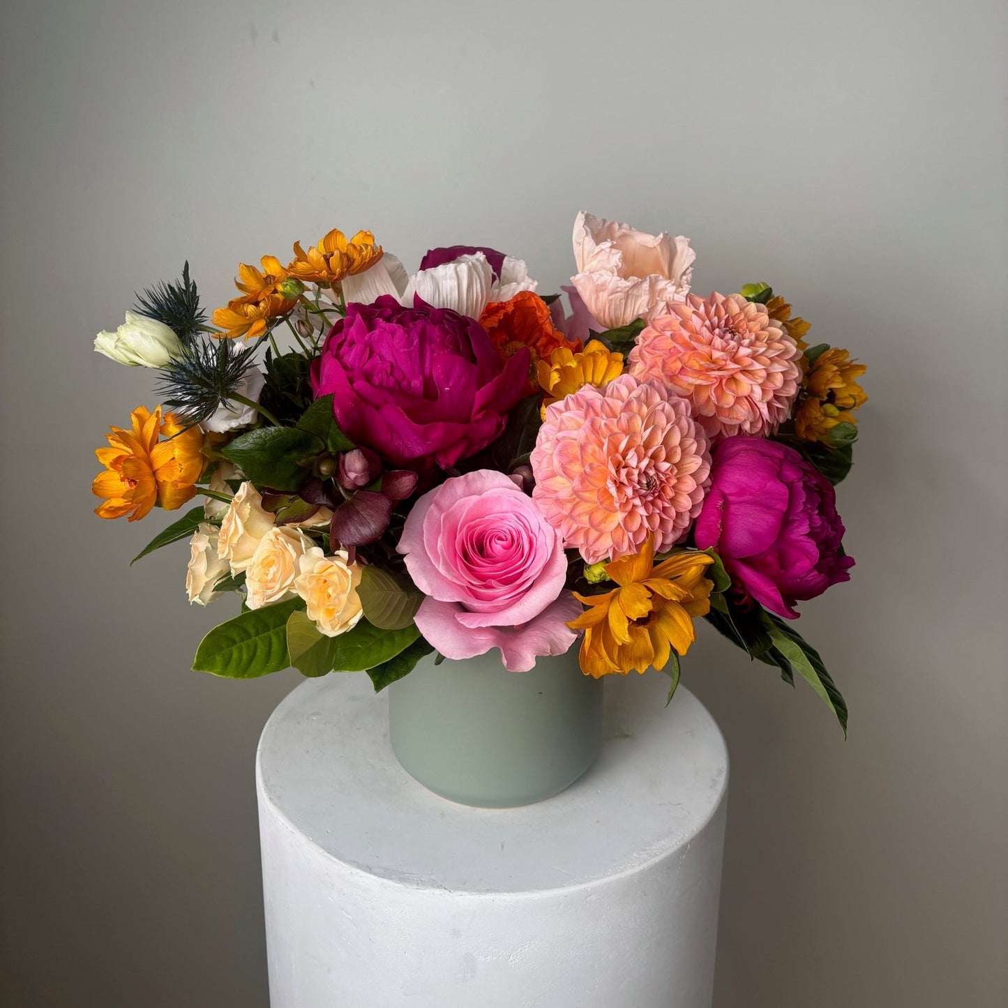 Bouquet of colorful flowers in a white container against a plain background