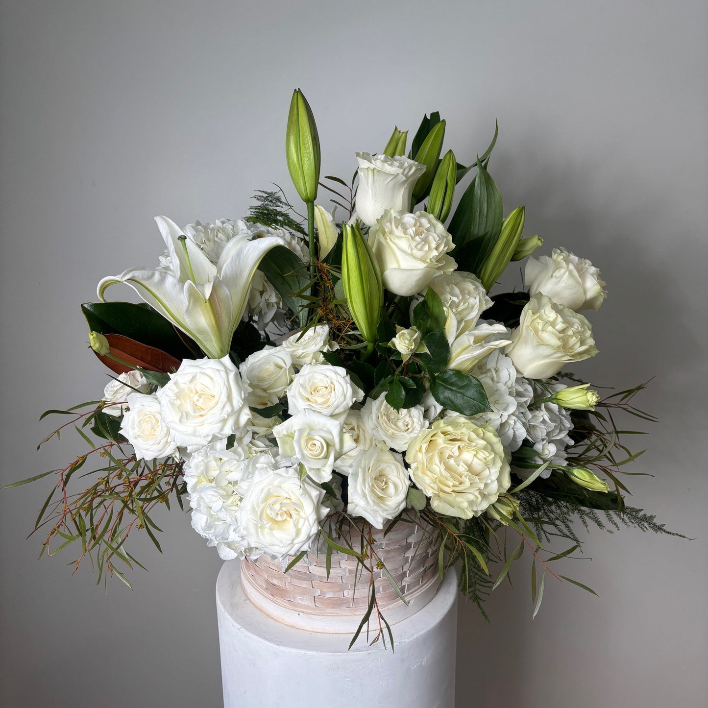Bouquet of white flowers in a white paper cone against a plain background