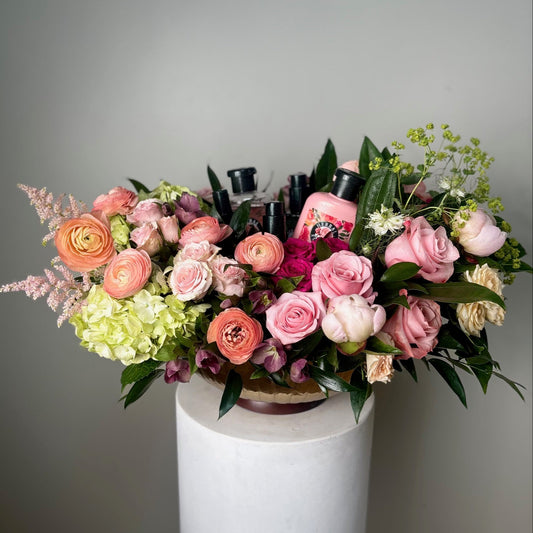 Bouquet of flowers with a bottle of perfume on a white pedestal against a gray background