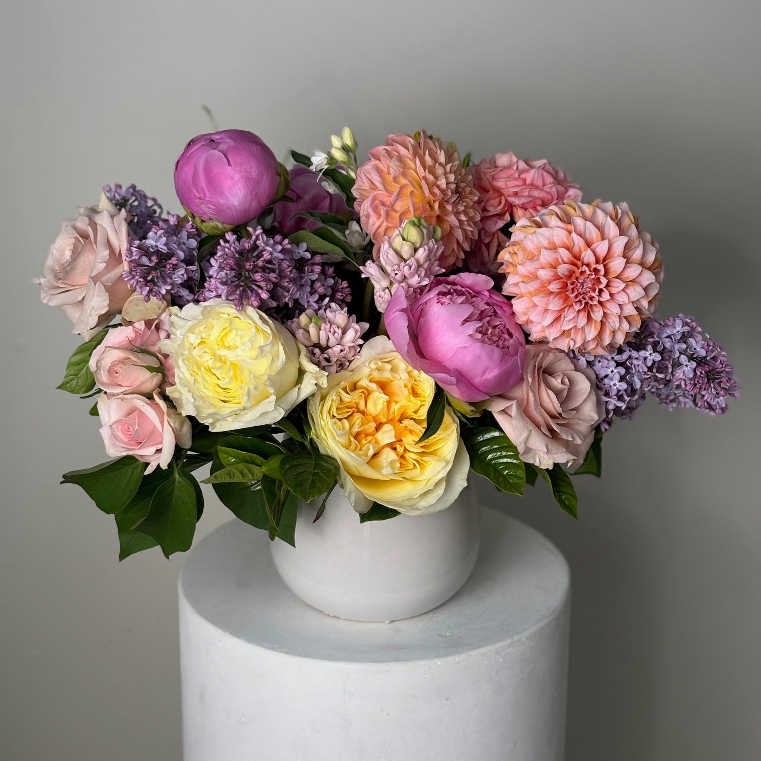 Bouquet of colorful flowers in a white vase on a gray background