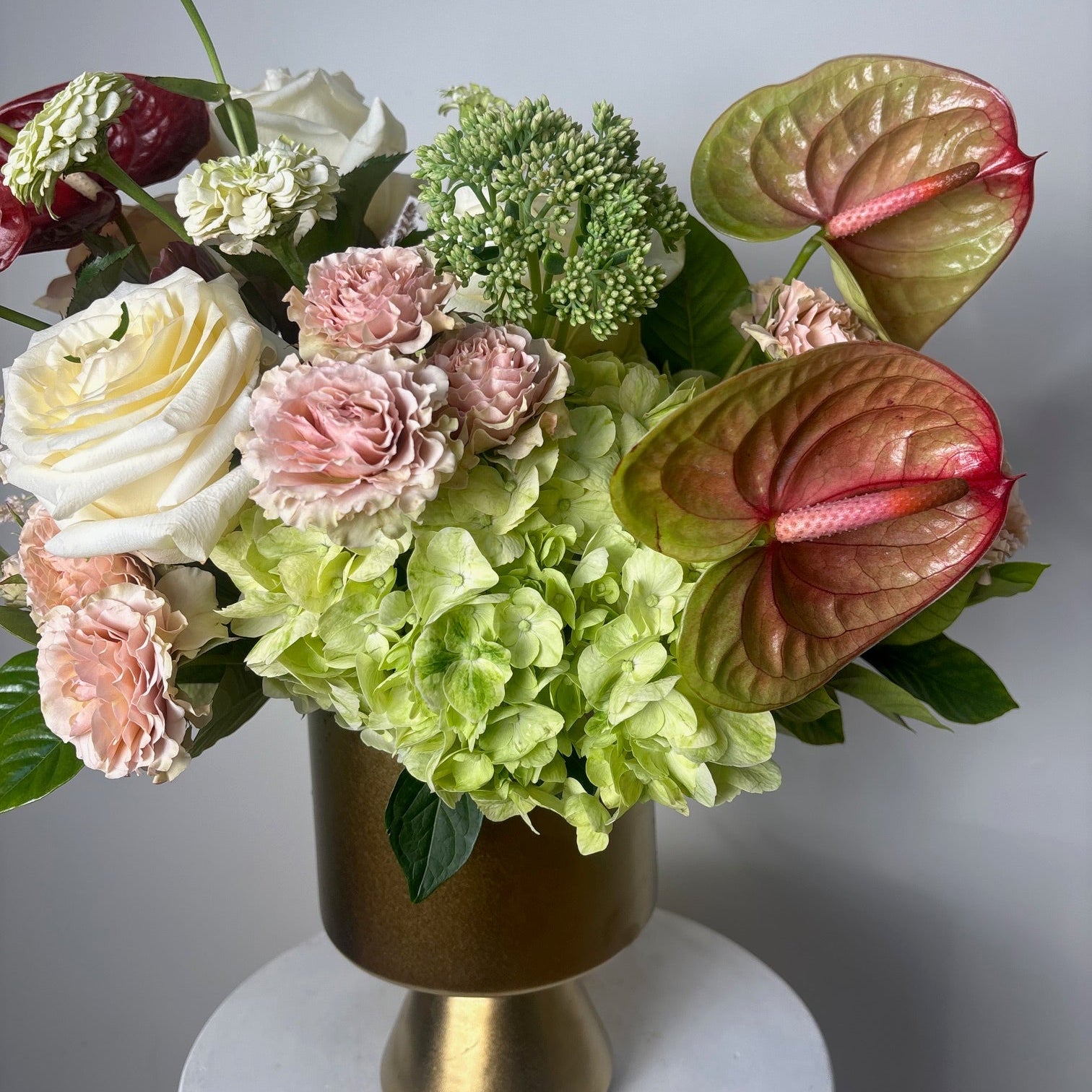 Floral arrangement with green and pink flowers on a gray background
