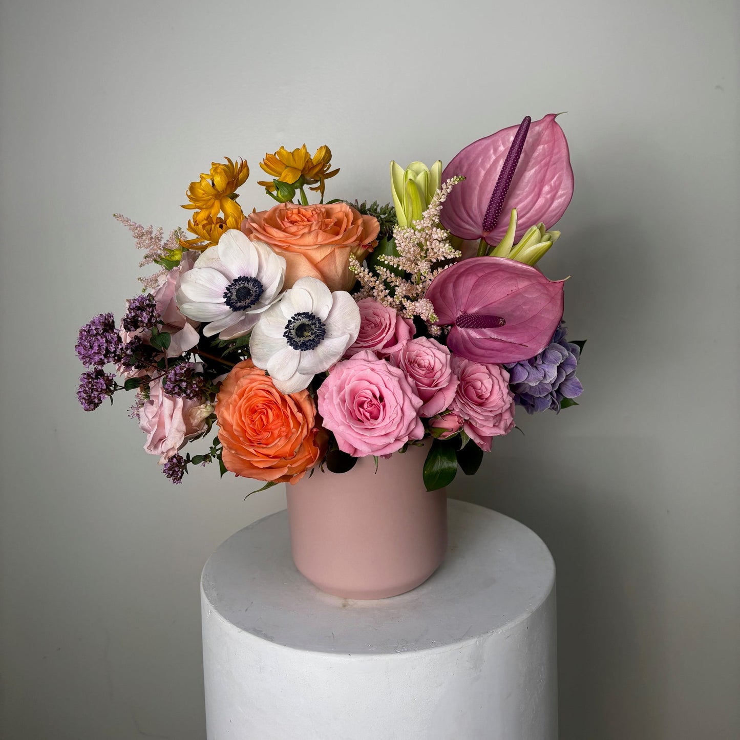 Colorful bouquet of flowers in a white vase on a light gray background
