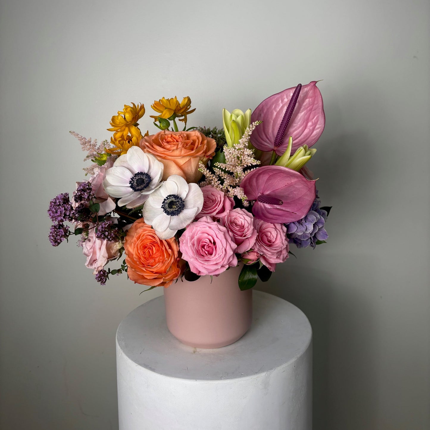 Pastel bouquet of flowers on a white pedestal against a gray background