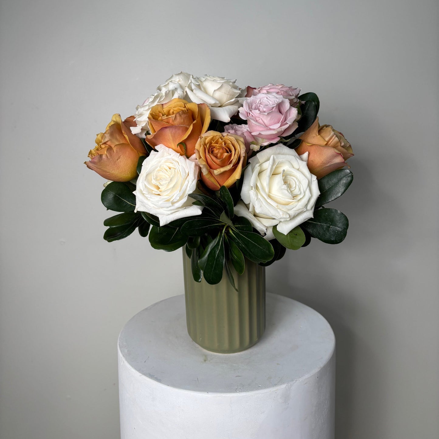 Bouquet of flowers on a white pedestal against a gray background
