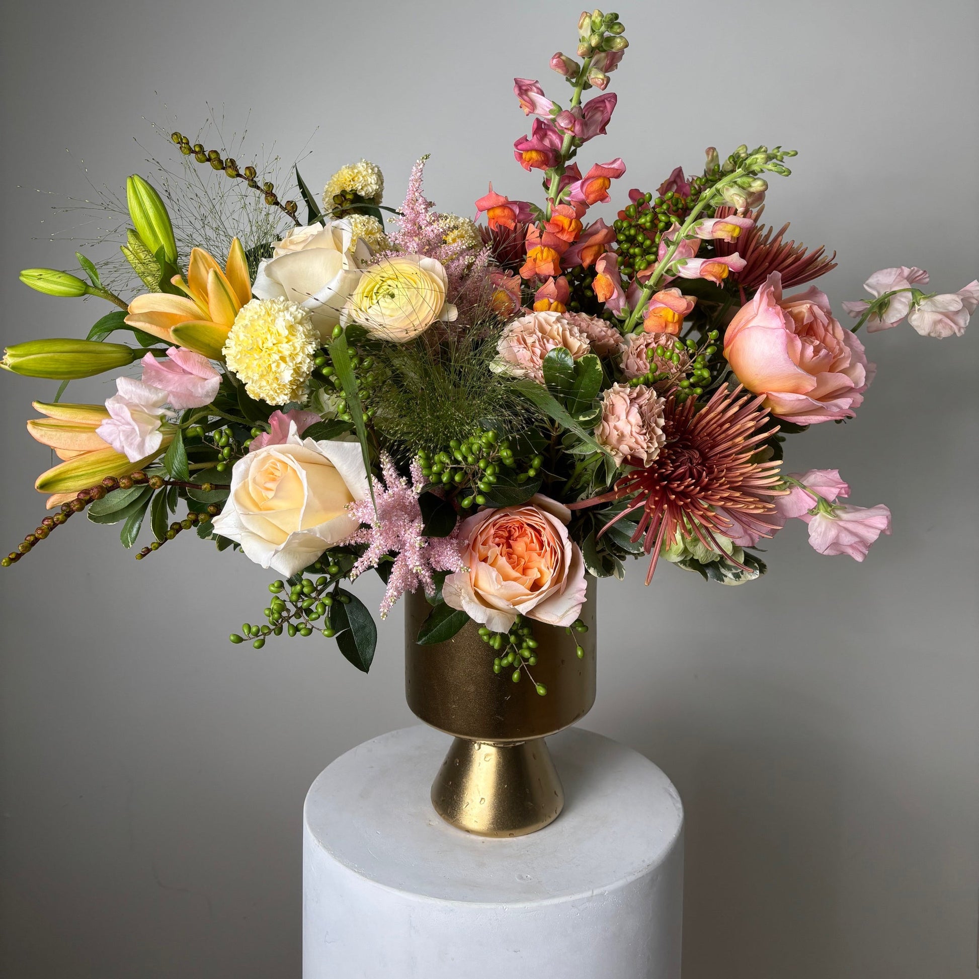 Colorful flower arrangement with a gold and white decorative object on a gray background