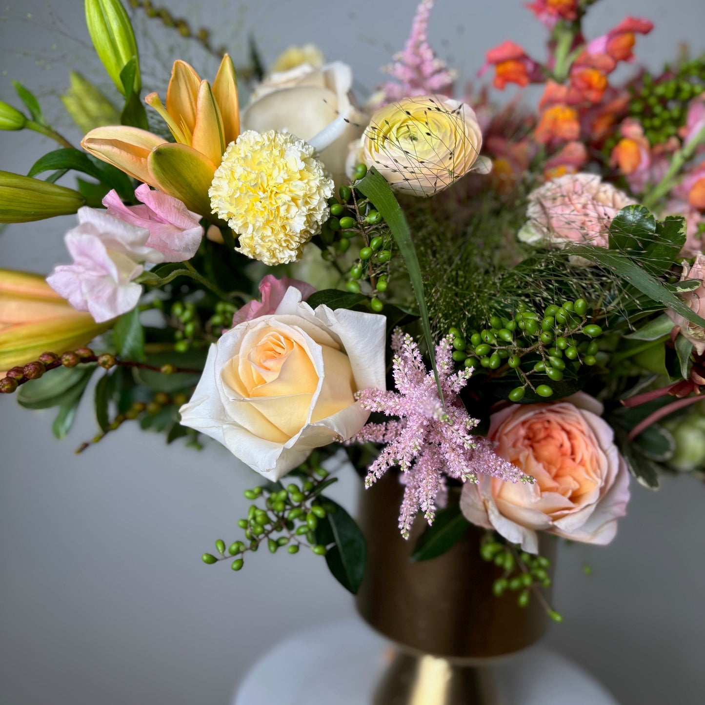 Floral arrangement in a gold vase on a gray background