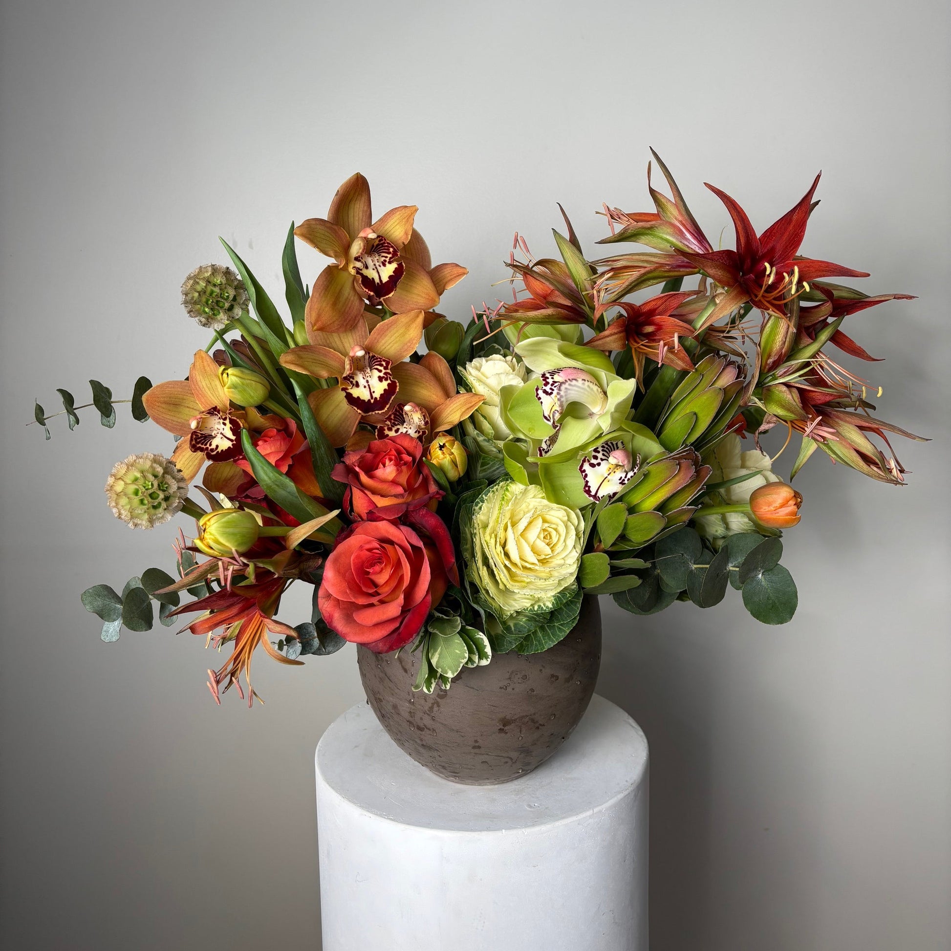 Colorful floral arrangement spilling out of a cylindrical container on a neutral background