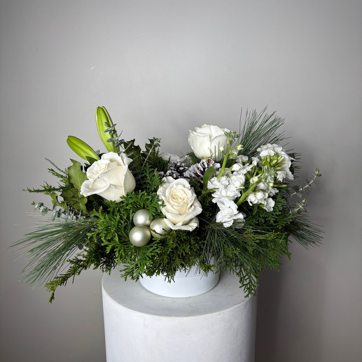 Decorative floral arrangement with white flowers and greenery on a plain background