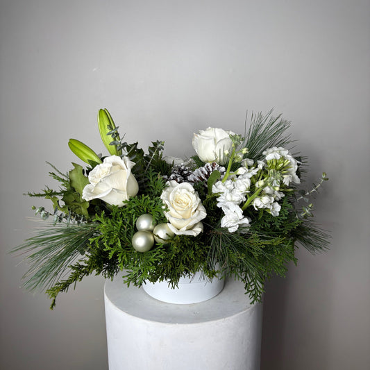 Decorative floral arrangement with white flowers and greenery on a plain background