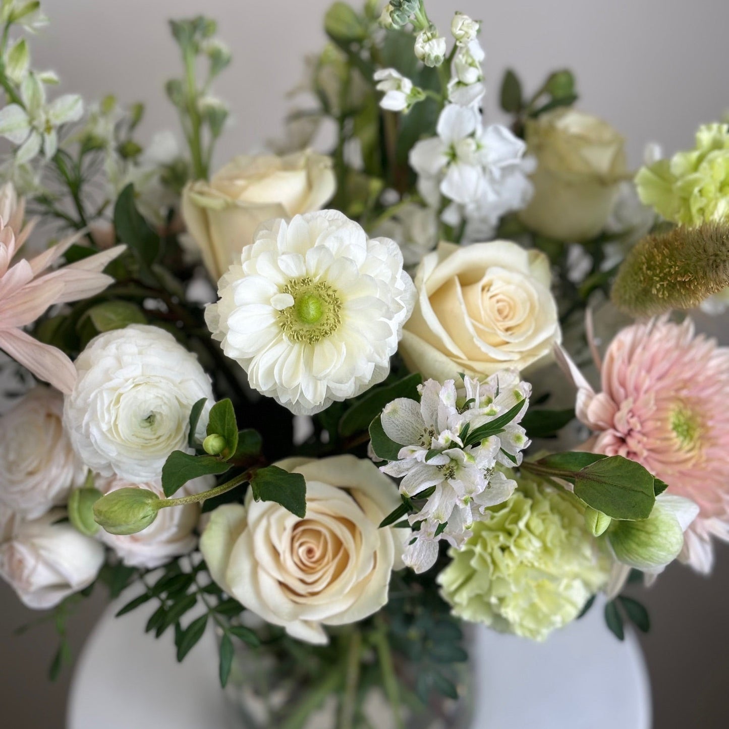 Bouquet of flowers including roses and chrysanthemums on a white surface.