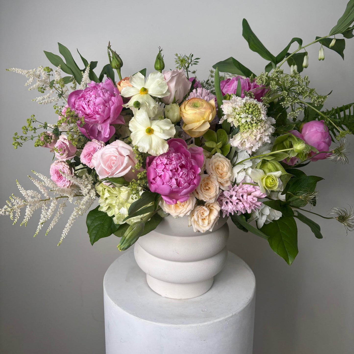 Bouquet of flowers with a white cylindrical container on a gray background
